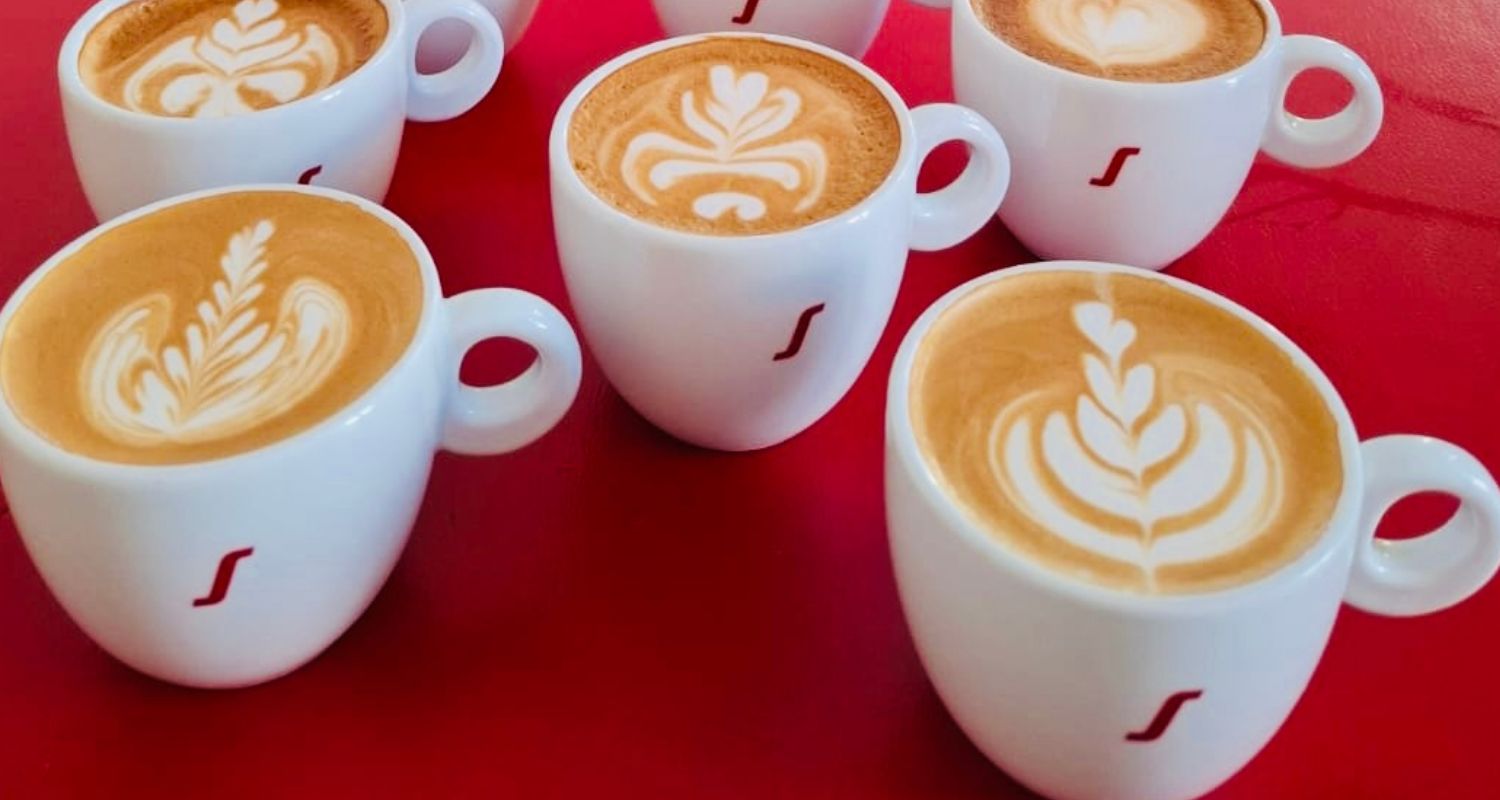 mehrere Tassen mit Cappuccino und Latte Art
