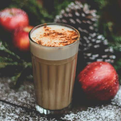 ein Latte Macchiato im Glas vor weihnachtlicher Dekoration