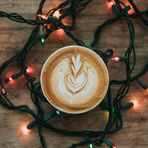 Ein Cappuccino mit Latte Art vor einer Lichterkette